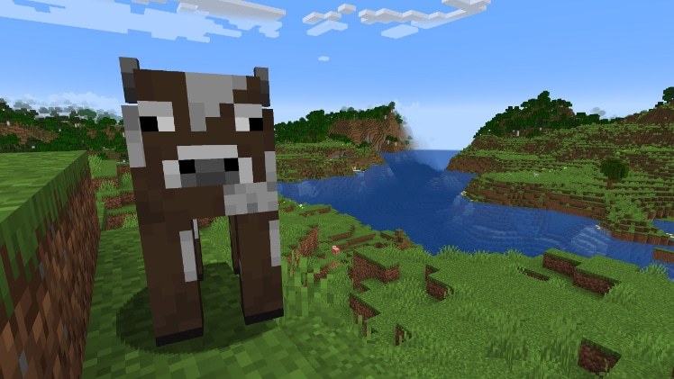 A Minecraft cow standing on grass beside a river