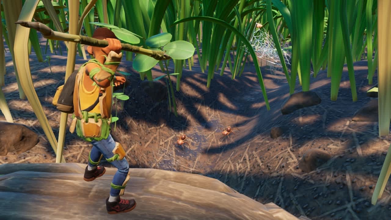 Grounded player carrying a spear above red ants in tall grass