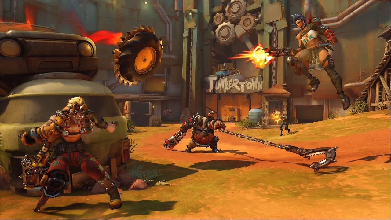 Three Junker heroes battling in front of the Junkertown sign in Overwatch